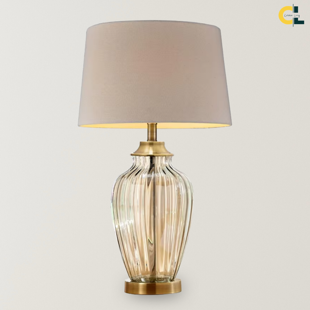 Aquila glass table lamp with a champagne-tinted ribbed base, bronze metal accents, and off-white linen shade, designed for soft ambient lighting on bedside tables, consoles, and living room side tables.
