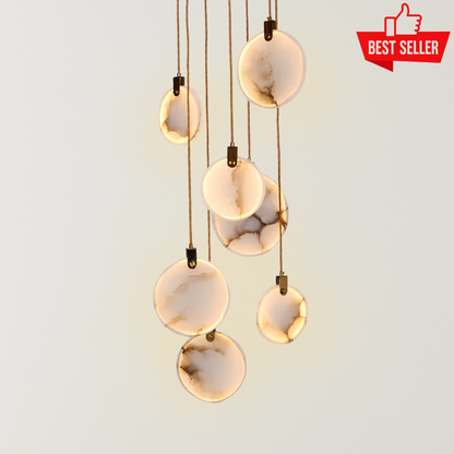 Eclisse marble chandelier with glowing round marble-effect LED pendants, warm ambient lighting, and slim hanging cords against a neutral background.