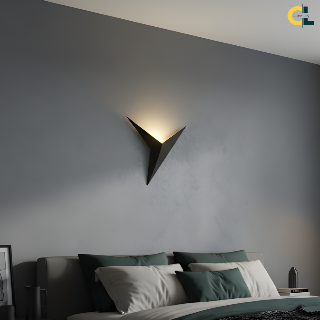 Gael Triangle LED Wall Lamp with a black geometric iron frame and soft upward warm glow, styled above a bed for minimalist bedrooms, living rooms, corridors, aisles, and modern Nordic interiors.