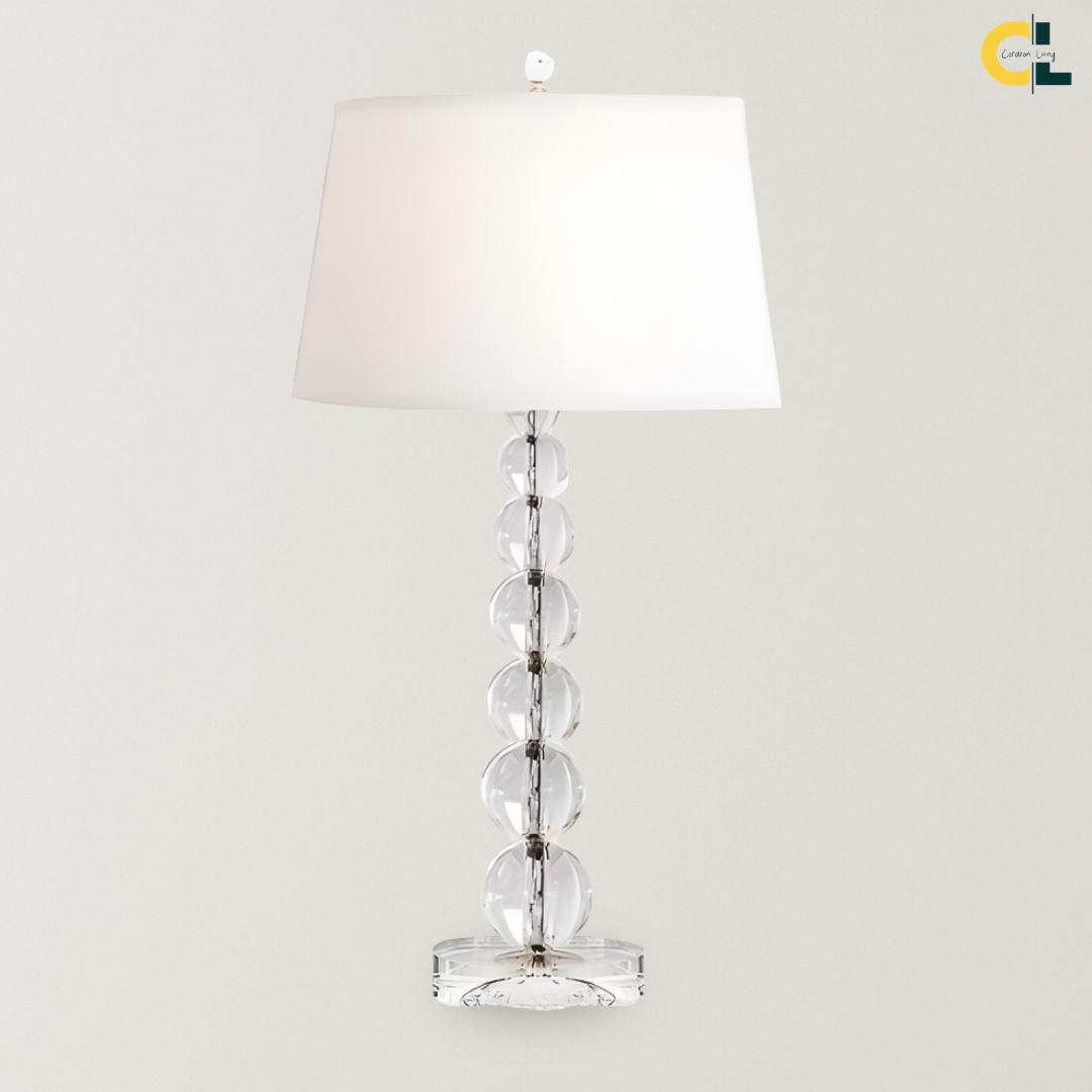 Merlin crystal ball table lamp with a stacked clear glass sphere base and white fabric shade, designed as a refined bedside, desk, console, or living room accent lamp.