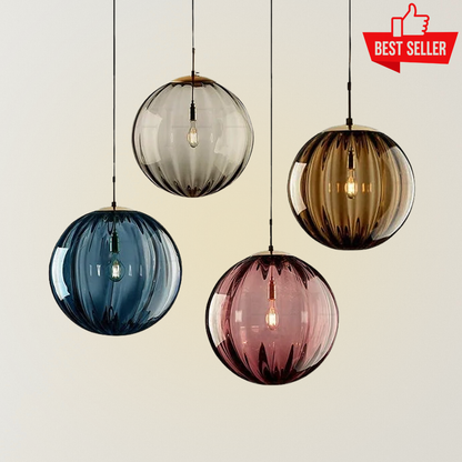 Pompel minimalist glass pendant lights with ribbed spherical shades in blue, smoke, pink, and amber finishes, each glowing with a warm exposed bulb.