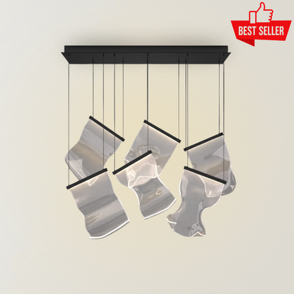 Soul chandelier with translucent layered acrylic panels, black suspension frame, and soft integrated lighting, creating a sculptural modern statement against a neutral background.